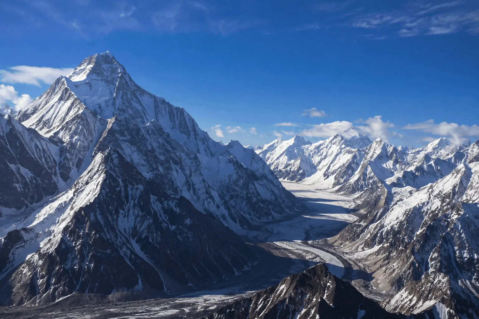 High-altitude photograph of K2 and surrounding jagged peaks and glaciers within the Karakoram mountain range of Pakistan. Mountain Range Peaks