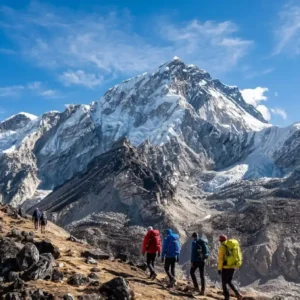 Group of trekkers with colorful backpacks hiking on a rocky trail toward snow-capped peaks on the Mount Everest Base Camp trek in Nepal.