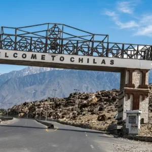 Welcome to Chilas entrance gate over the Karakoram Highway with snow-capped mountain peaks in the background.