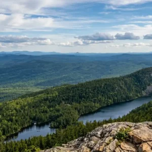 High-angle view of a glacial pond surrounded by forested mountain ridges in the Western Maine region. Maine Mountains