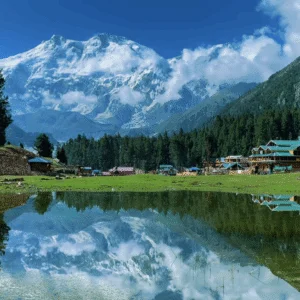 The iconic crystal clear reflection lake at Fairy Meadows in Pakistan showcasing the snow-covered north face of Nanga Parbat mountain with traditional wooden resorts.